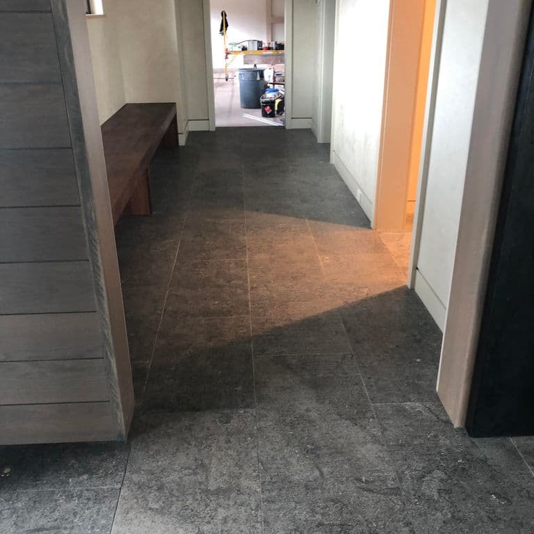 Application image for Highland Limestone. The image shows this material being used in an interior floor application. The surface finish shown is antiqued. The dominant color shown is gray. The color mix creates a cool feeling. Regular and random color patterns.