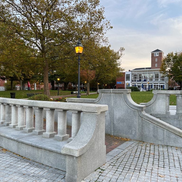 Feature image for Chelmsford Gray Granite. The image shows this material being used for architectural elements and patio pavers. The surface finish shown is honed. The dominant color shown is gray; with blue and white secondaries. The color mix creates a warm feeling. Fine speckled color pattern.