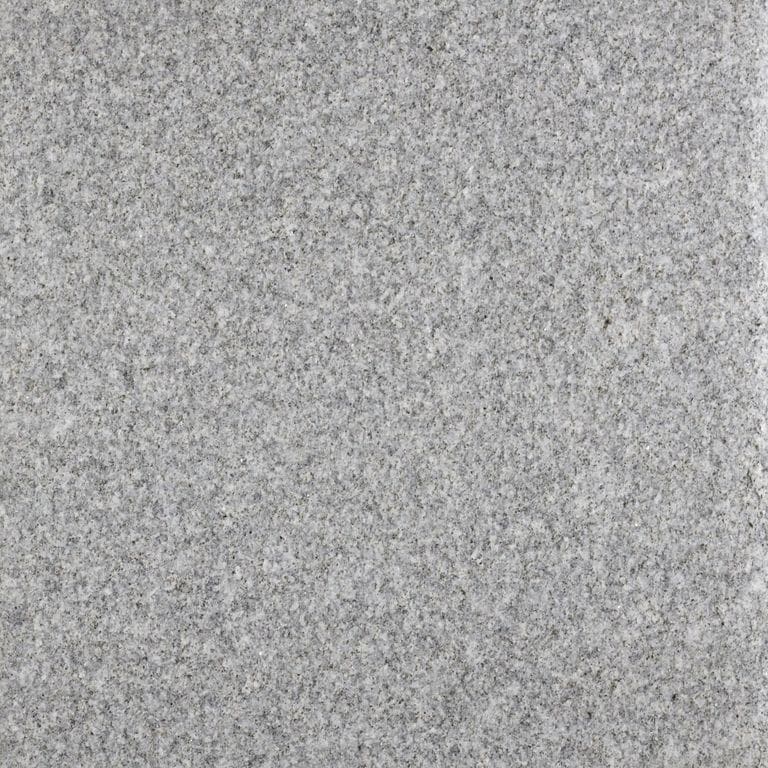 Close-up image for Chester Gray Granite. The surface finish shown is flamed. The dominant color shown is gray; with beige and white secondaries. The color mix creates a cool feeling. Solid and fine speckled color patterns. Contains some mica and mineral inclusions.