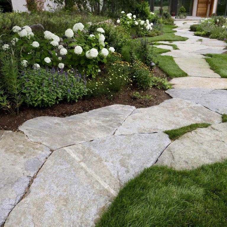 Feature image for Dodlin Hill Granite. The image shows this material being used in a path pavers application. The dominant color shown is gray; with pink, white and cream secondaries. Exhibits "movement". Fine speckled, blotched, veined and cloudy color patterns.