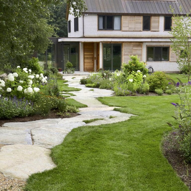 Application image for Dodlin Hill Granite. The image shows this material being used in a path pavers application. The surface finish shown is natural cleft. Dominant colors shown are beige, gray and cream; with white and tan secondaries. The color mix creates a warm feeling. Speckled color pattern.