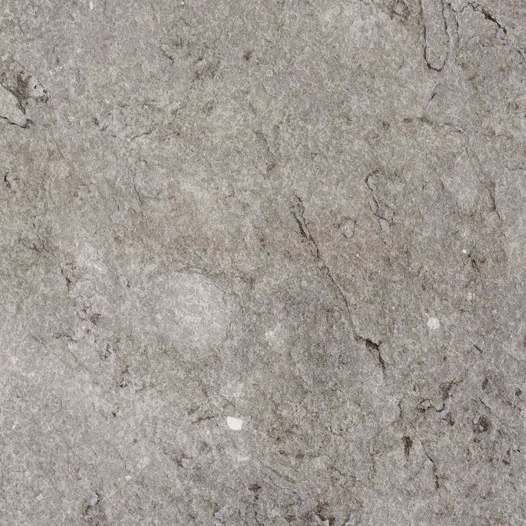 Close-up image for Dawn Haze Limestone. The surface finish shown is flamed. The dominant color shown is gray; with beige, brown, green, purple, white and tan secondaries. Exhibits "movement". Random, blotched and cloudy color patterns. Contains mineral inclusions.