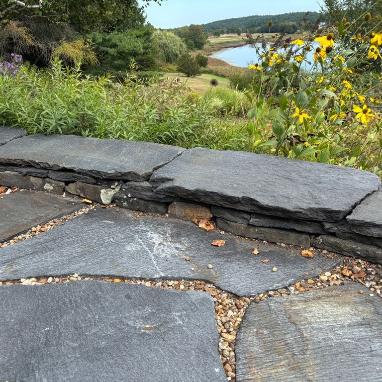 Application image for Goshen Stone. The image shows this material being used in a patio pavers application. The surface finish shown is natural cleft. The dominant color shown is gray. The color mix creates a warm feeling.