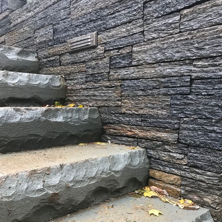 The image shows this material being used in a landscape wallstone application. Streaked color pattern.