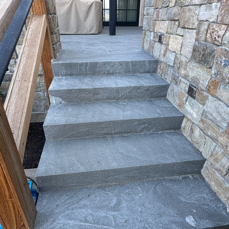 Application image for Granite - Jet Mist. The image shows this material being used in a monolithic steps application. The dominant color shown is gray. The color mix creates a cool feeling.