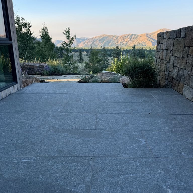 Application image for Granite - Jet Mist. The image shows this material being used in a patio pavers application. The surface finish shown is flamed. The dominant color shown is gray.