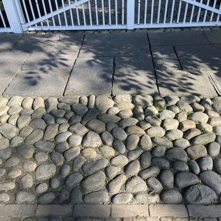Application image for Beach Rounds. The image shows this material being used in a driveway aprons application. The surface finish shown is . The dominant color shown is gray. The color mix creates a warm feeling. Regular color pattern.