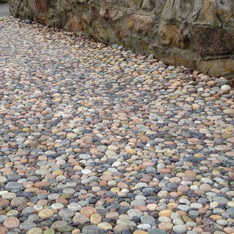 Application image for Beach Rounds. The image shows this material being used in a driveway pavers application. The surface finish shown is . Dominant colors shown are gray and tan. The color mix creates a warm feeling. Regular color pattern.