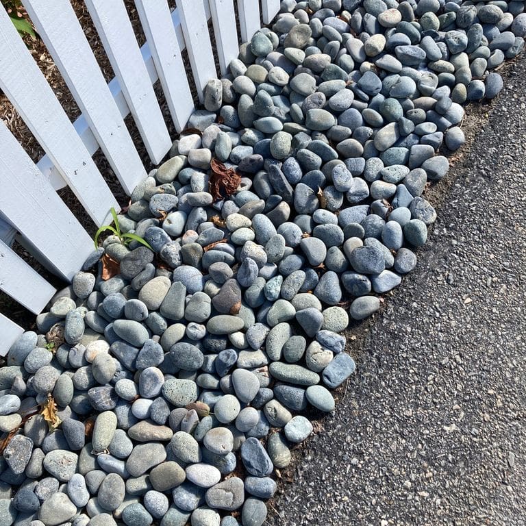Application image for Beach Rounds. The image shows this material being used in a landscape curbing &amp; edging application. The surface finish shown is a combination of natural and weathered. The dominant color shown is gray; with blue, green and white secondaries. The color mix creates a cool feeling.