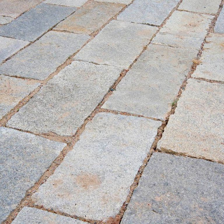 Application image for Reclaimed Rustic Granite. The image shows this material being used in a patio pavers application. The surface finish shown is . The dominant color shown is gray. The color mix creates a warm feeling.