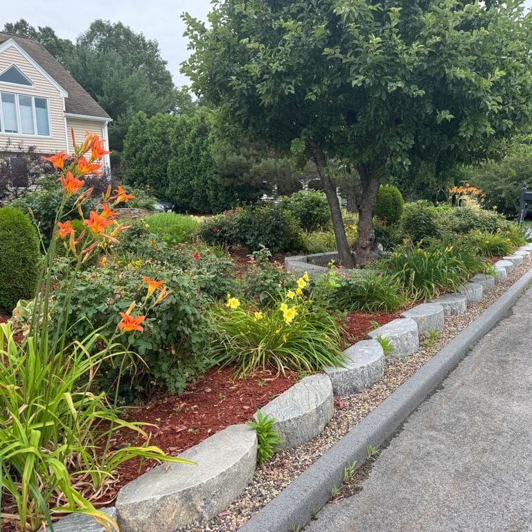 Application image for Reclaimed Granite D-Radius Curbstone. The image shows this material being used in a landscape curbing &amp; edging application. The dominant color shown is gray.