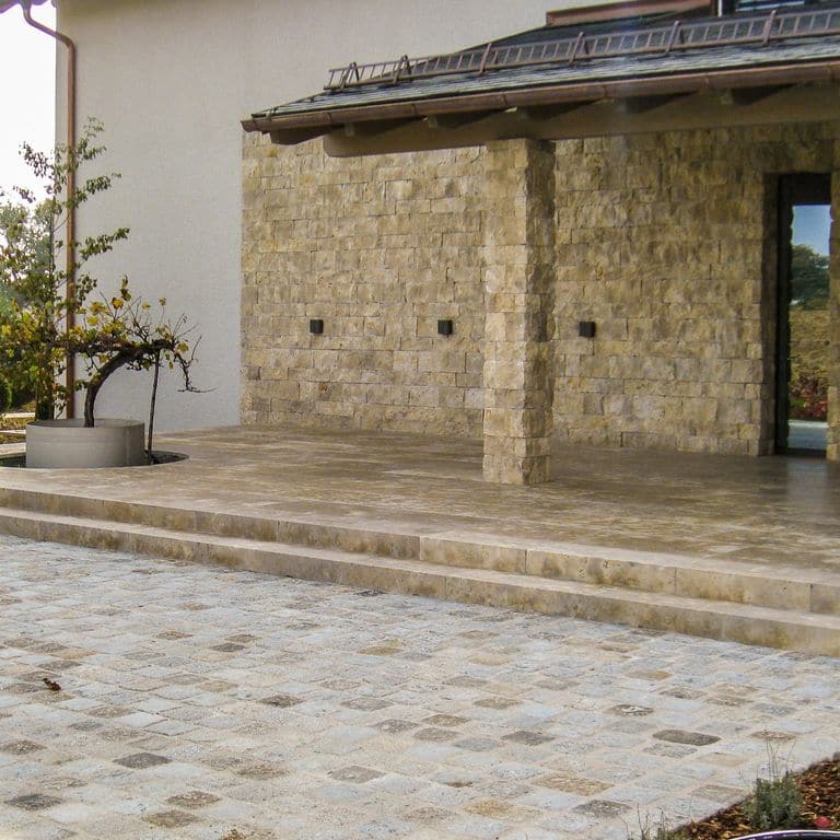 Application image for Bavarian Dolomite - Gray. The image shows this material being used for patio pavers, treads, full bed veneer and thin veneer. The surface finish shown is a combination of honed and split-face. Dominant colors shown are brown and gray. The color mix creates a warm feeling. Blotched color pattern. Contains voids.