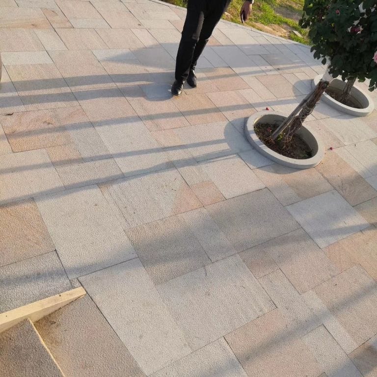 Application image for Granite - Yangtze Yellow. The image shows this material being used in a patio pavers application. Dominant colors shown are gray and tan; with beige, brown, orange/rust, pink and purple secondaries. Exhibits "movement" and the color mix creates a warm feeling. Fine speckled color pattern.