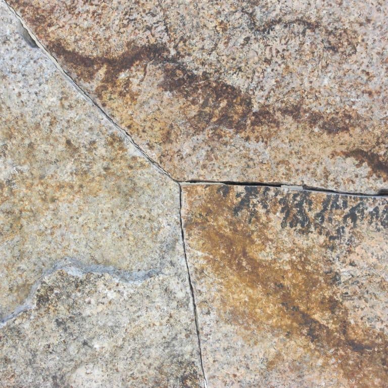 Close-up image for Golden Granite Block - Oversized Quarry Skins. The surface finishes shown are split-face and weathered. Dominant colors shown are beige, brown, gray and tan; with orange/rust, purple, white and cream secondaries. Exhibits "movement" and the color mix creates a warm feeling. Random, speckled, blotched, veined, swirled and streaked color patterns. Contains some mica.