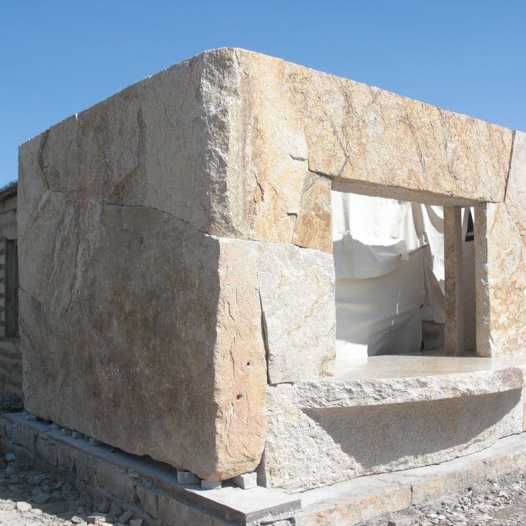 Feature image for Golden Granite Block - Oversized Quarry Skins. The image shows this material being used in a full bed veneer application. Dominant colors shown are beige, gray, tan and cream; with orange/rust and white secondaries. Exhibits "movement" and the color mix creates a warm feeling. Random, speckled, fine speckled and streaked color patterns. Contains some mica.