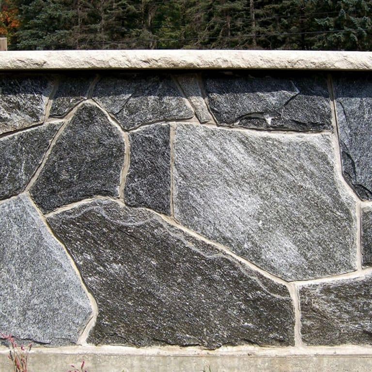 Close-up image for Chester Village Granite Blend. The surface finish shown is split-face with flat plane. The dominant color shown is gray; with beige, black, brown, green, purple, white and cream secondaries. Exhibits "movement". Fine speckled and streaked color patterns. Contains lots of mica and mineral inclusions.
