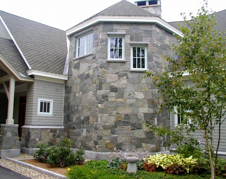 Application image for Chester Village Granite Blend. The image shows this material being used for full bed veneer and thin veneer. The surface finish shown is split-face with flat plane. The dominant color shown is gray; with brown, orange/rust, purple and tan secondaries. The color mix creates a cool feeling. Regular color pattern.