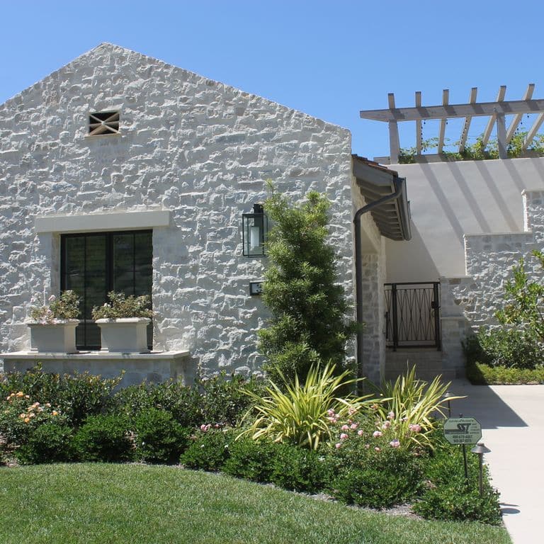 Application image for Tundra Cream Limestone. The image shows this material being used for full bed veneer and thin veneer. The surface finish shown is split-face. The dominant color shown is gray; with a white secondary. The color mix creates a cool feeling. Regular color pattern.