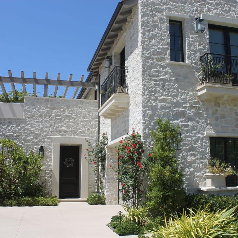 Application image for Tundra Cream Limestone. The image shows this material being used for full bed veneer and thin veneer. The surface finish shown is split-face. The dominant color shown is gray; with a white secondary. Regular color pattern.