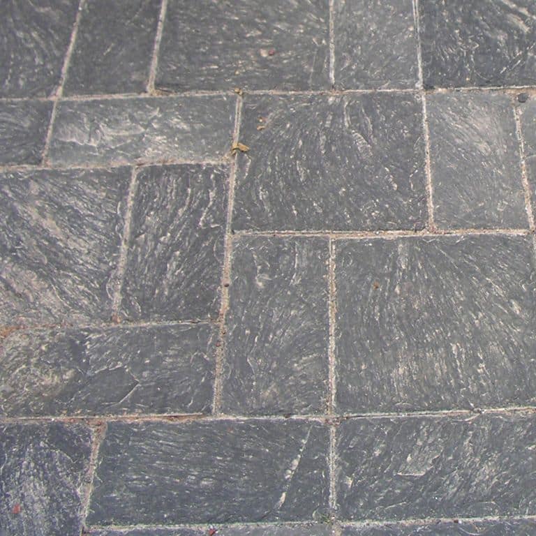 Close-up image for Vermont Slate - Black. The surface finish shown is split-face. The dominant color shown is gray; with a purple secondary. Exhibits "movement" and the color mix creates a cool feeling. Regular and streaked color patterns.