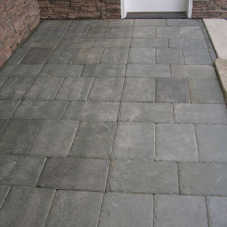 Feature image for Vermont Slate - Green. The image shows this material being used for path pavers and patio pavers. The dominant color shown is gray; with brown, green and purple secondaries. Exhibits "movement" and the color mix creates a cool feeling. Regular and cloudy color patterns.