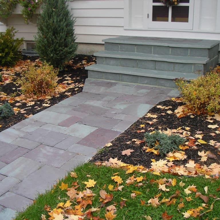 Feature image for Vermont Slate - Mottled. The image shows this material being used in a path pavers application. Dominant colors shown are blue, green, gray and purple. Exhibits "movement" and the color mix creates a cool feeling. Blotched color pattern.