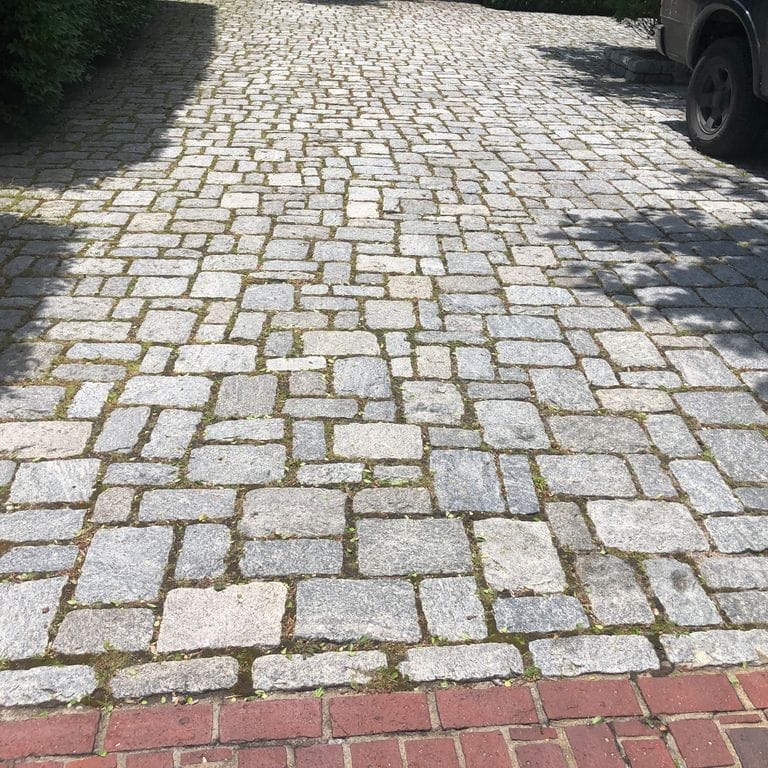The image shows this material being used in a driveway pavers application.