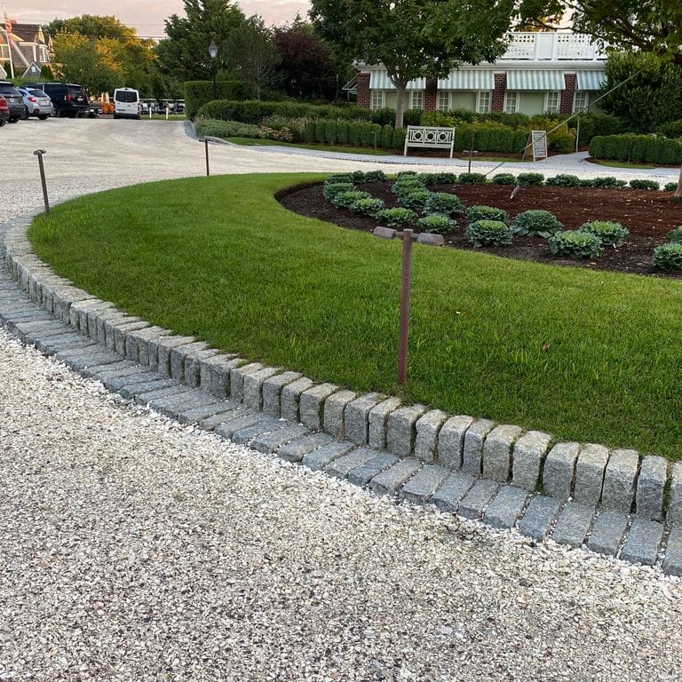 Application image for Granite Cobblestones - Gray. The image shows this material being used in a landscape curbing &amp; edging application. This is a landscape stone for outdoor commercial and residential applications. Suitable for general use, freeze-thaw conditions, low heat absorption surfaces, high traffic areas and low slipperiness surfaces situations. Relatively moderate in price.