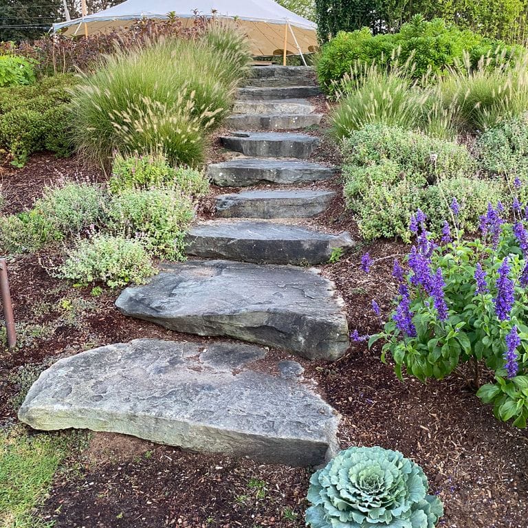 Feature image for Pennsylvania Fieldstone. The image shows this material being used in a monolithic steps application. The dominant color shown is gray; with blue, green, pink, purple, white, tan and cream secondaries. Exhibits "movement". Random, blotched and swirled color patterns.