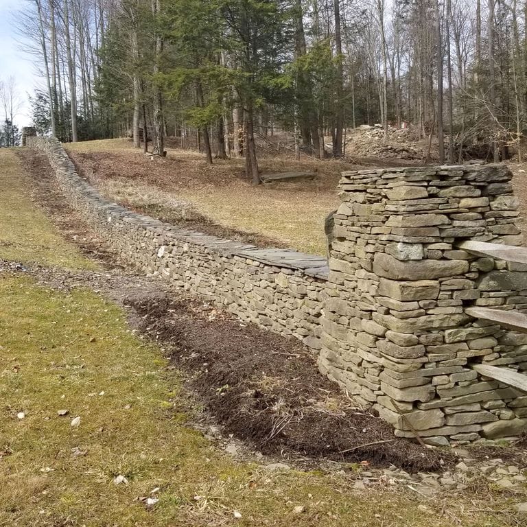 The image shows this material being used in a landscape wallstone application.