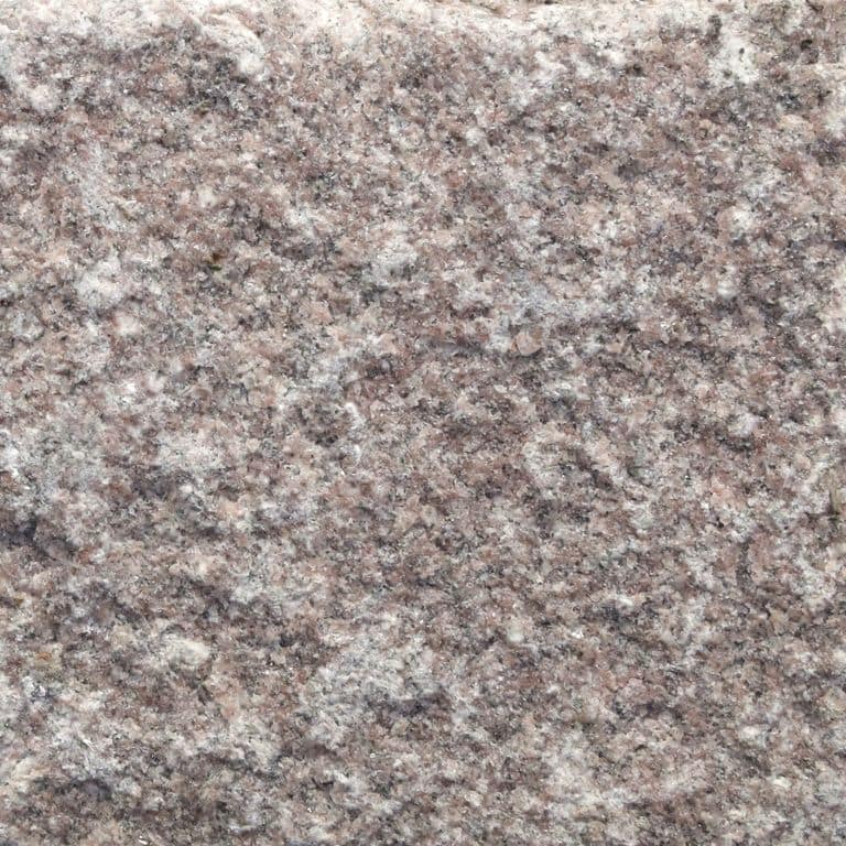 Close-up image for Granite Cobblestones - Dusty Rose. The surface finishes shown are split-face, split-face with flat plane and tumbled. Dominant colors shown are gray and purple; with beige, red and white secondaries. Exhibits "movement" and the color mix creates a warm feeling. Regular and blotched color patterns. Contains some mica.