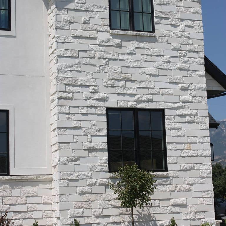 Application image for Blanco Limestone. The image shows this material being used for full bed veneer and thin veneer. The surface finish shown is a combination of honed and split-face. The dominant color shown is white; with a cream secondary. The color mix creates a warm feeling. Solid color pattern.