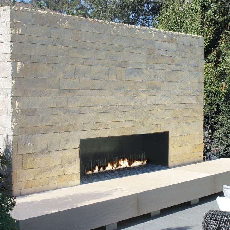 Feature image for Regent Buff Limestone. The image shows this material being used for fireplace surround, full bed veneer and thin veneer. Dominant colors shown are beige and cream; with gray and white secondaries. Exhibits "movement" and the color mix creates a warm feeling. Regular color pattern.
