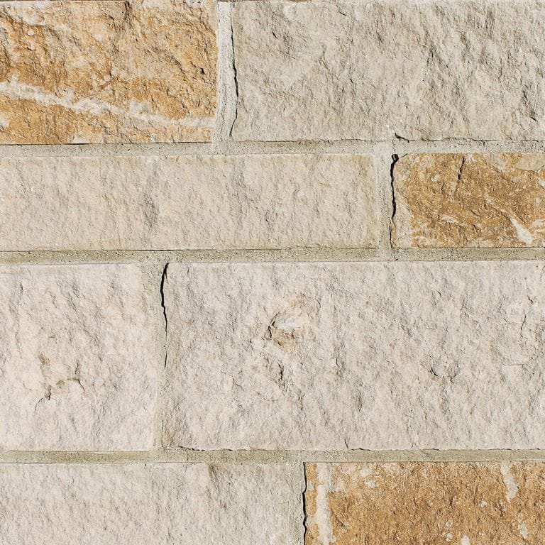 Close-up image for Honey Buff Limestone. The surface finish shown is split-face. Dominant colors shown are beige and tan; with brown, gray, orange/rust and cream secondaries. Exhibits "movement" and the color mix creates a warm feeling. Regular, swirled and cloudy color patterns.