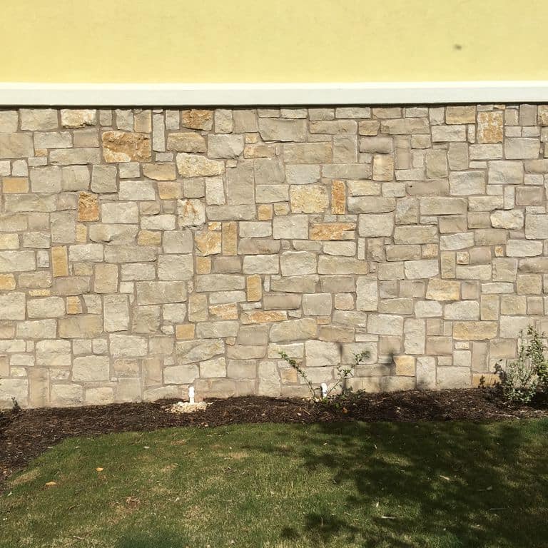 Application image for Honey Buff Limestone. The image shows this material being used for full bed veneer and thin veneer. The surface finish shown is split-face. Dominant colors shown are gray and tan; with a brown secondary. The color mix creates a warm feeling. Regular color pattern.