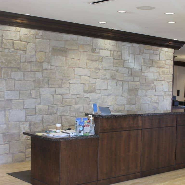 Application image for Limestone - Honey Buff. The image shows this material being used for full bed veneer, thin veneer and interior cladding. The surface finish shown is split-face. Dominant colors shown are gray and tan. The color mix creates a warm feeling. Regular color pattern.