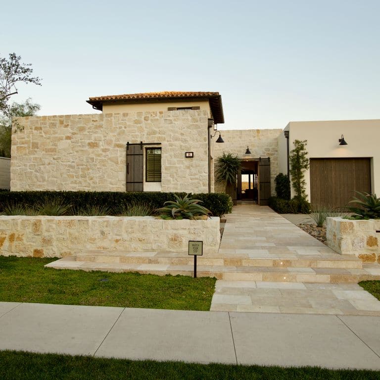 Application image for Honey Buff Limestone. The image shows this material being used for full bed veneer and thin veneer. The surface finish shown is split-face. Dominant colors shown are brown and tan; with gray and orange/rust secondaries. The color mix creates a warm feeling. Regular color pattern.