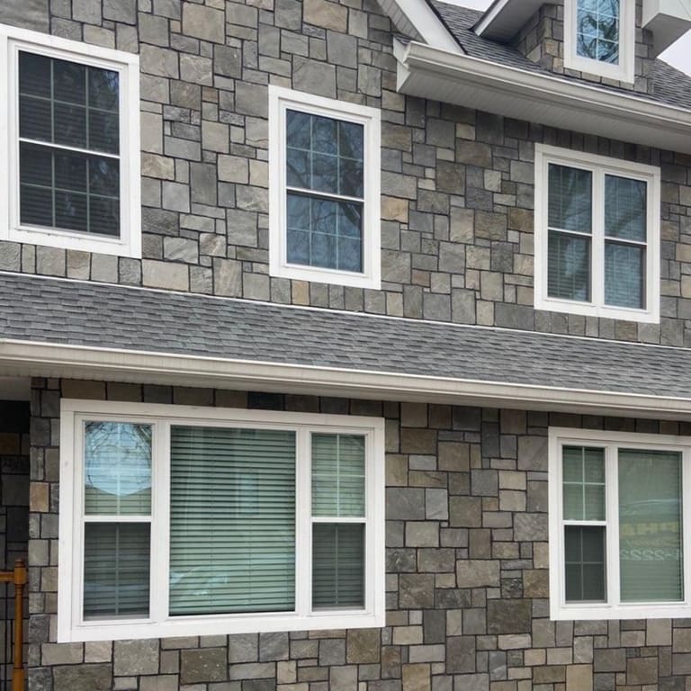 Feature image for Alpine Gray Quartzite. The image shows this material being used for full bed veneer and thin veneer. The dominant color shown is gray; with black, brown, green, purple and tan secondaries. Exhibits "movement" and the color mix creates a warm feeling. Random, fine speckled, streaked and cloudy color patterns.