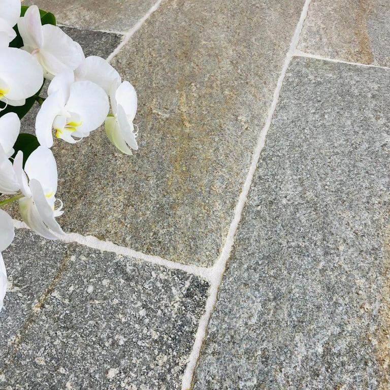 Application image for Pietra Italia Full Color Gneiss. The image shows this material being used in a patio pavers application. The surface finish shown is natural cleft. Dominant colors shown are beige and gray. The color mix creates a warm feeling.