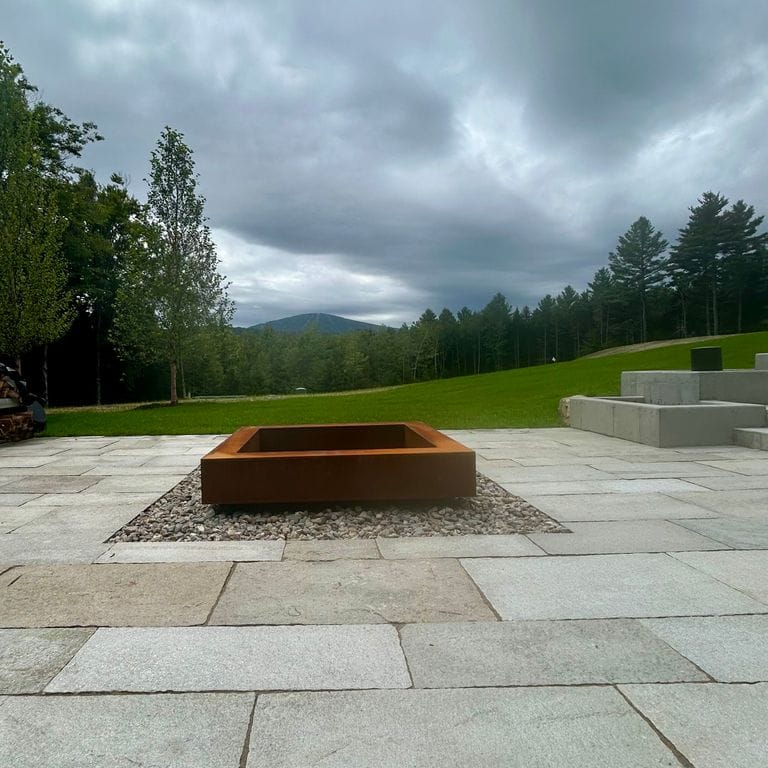 Application image for Pietra Italia Gneiss. The image shows this material being used in a patio pavers application. The surface finish shown is natural cleft. Dominant colors shown are beige and gray. Exhibits "movement". Regular, linear and cloudy color patterns. Contains some mica and mineral inclusions.