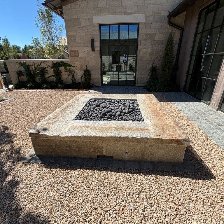 Application image for Reclaimed First Generation Granite Curbstone. The image shows this material being used in an outdoor fire concepts application. The surface finish shown is . Dominant colors shown are brown and gray.