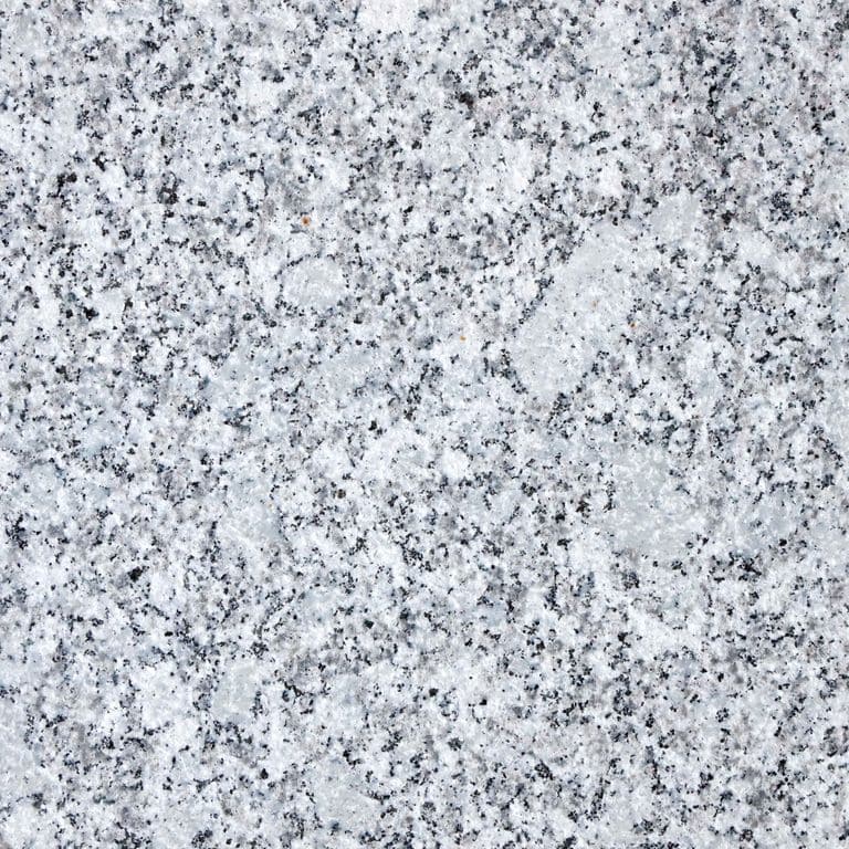 Feature image for Gray Ice Granite. The surface finish shown is flamed. Dominant colors shown are gray and white; with beige, black, pink, purple, white and cream secondaries. The color mix creates a cool feeling. Speckled and blotched color patterns. Contains some mica and mineral inclusions.