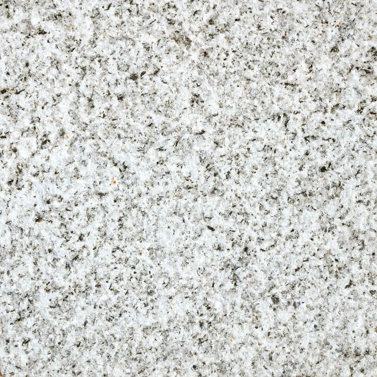 Feature image for Crystal White Granite. The surface finish shown is sand blasted. Dominant colors shown are gray and white; with beige, blue, pink, purple and cream secondaries. The color mix creates a cool feeling. Speckled color pattern. Contains some mica and mineral inclusions.