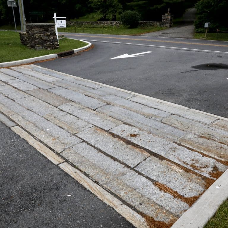 Application image for Granite - Reclaimed Third Generation Curbstone. The image shows this material being used in a driveway aprons application.