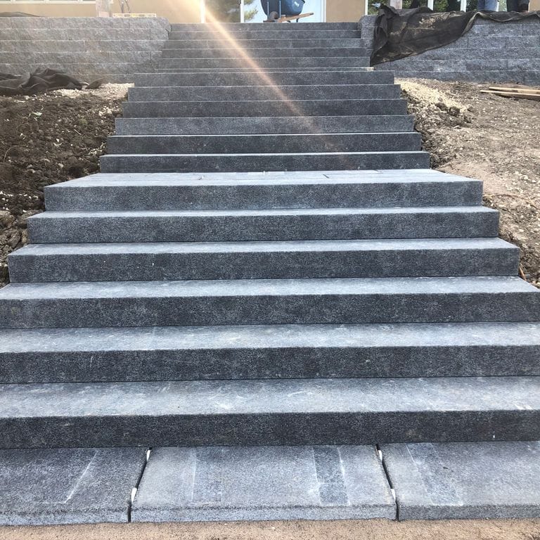 Application image for Superior Northern Granite. The image shows this material being used for monolithic steps and treads. Dominant colors shown are black and gray.
