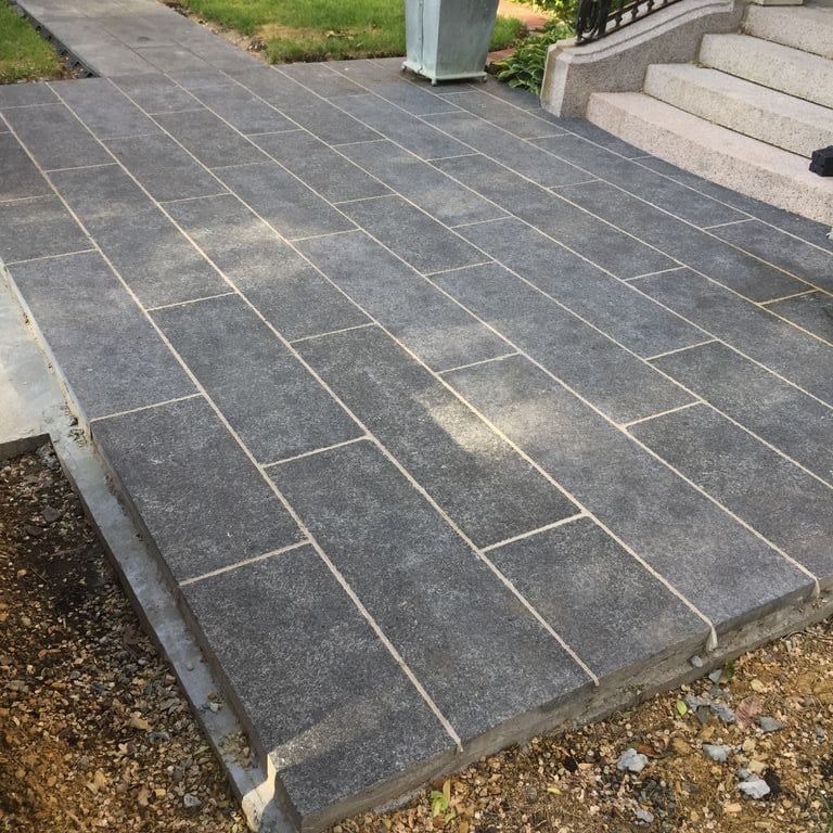 Application image for Superior Northern Granite. The image shows this material being used in a patio pavers application. Dominant colors shown are black and gray.