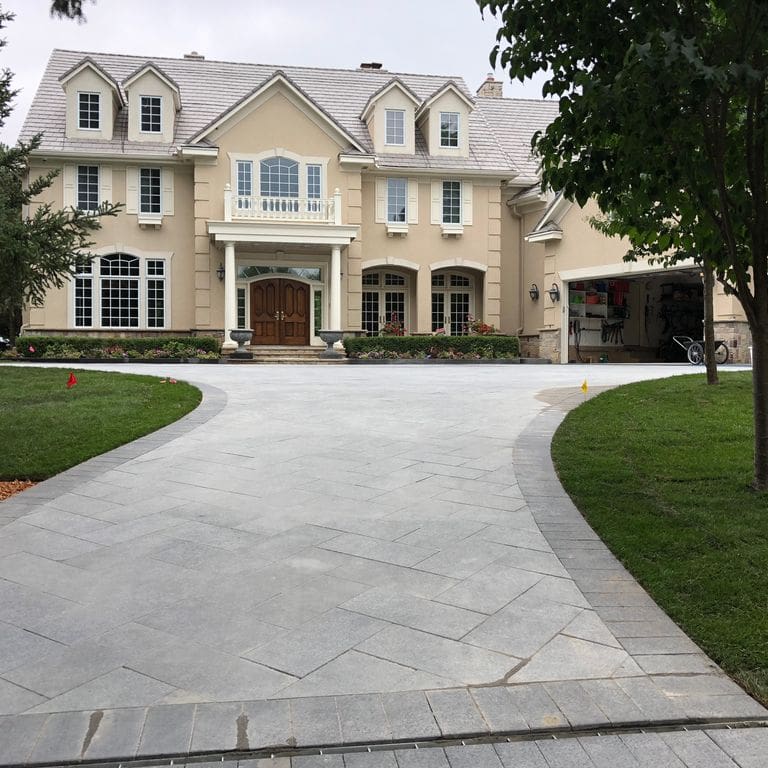Application image for Superior Northern Granite. The image shows this material being used in a driveway pavers application. Dominant colors shown are black and gray.