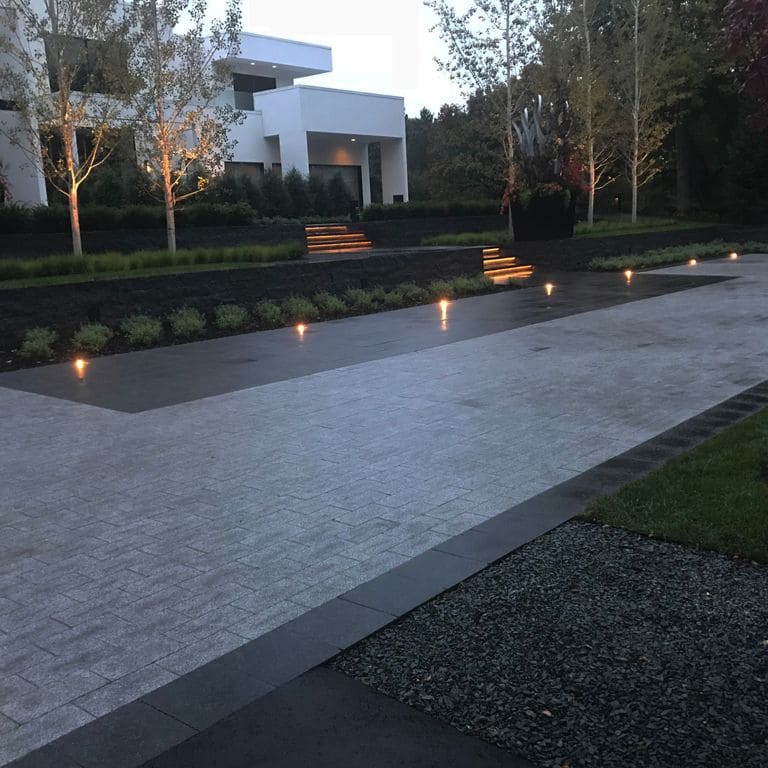 Application image for Superior Northern Granite. The image shows this material being used in a driveway pavers application. Dominant colors shown are black and gray.