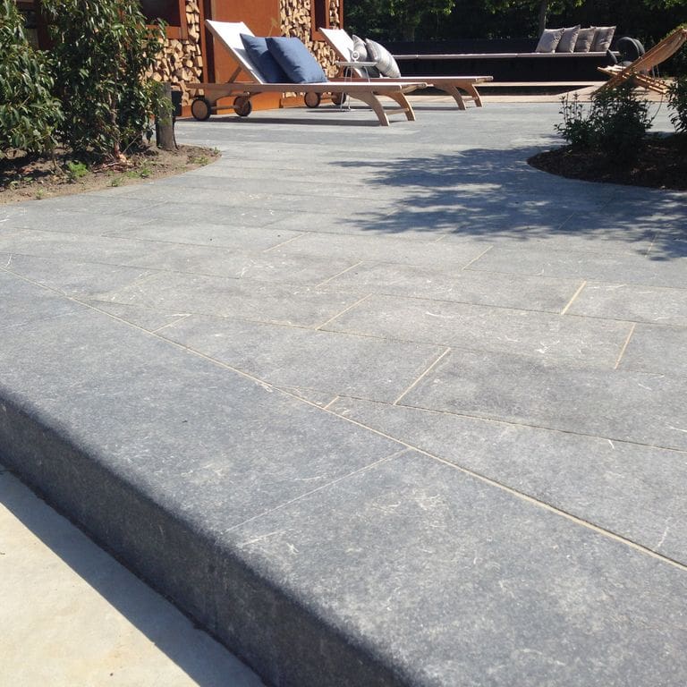 Feature image for Limestone - Kilkenny. The image shows this material being used for landscape curbing &amp; edging and patio pavers. The surface finish shown is flamed. Dominant colors shown are blue and gray; with blue, purple, white and cream secondaries. The color mix creates a cool feeling. Regular color pattern.