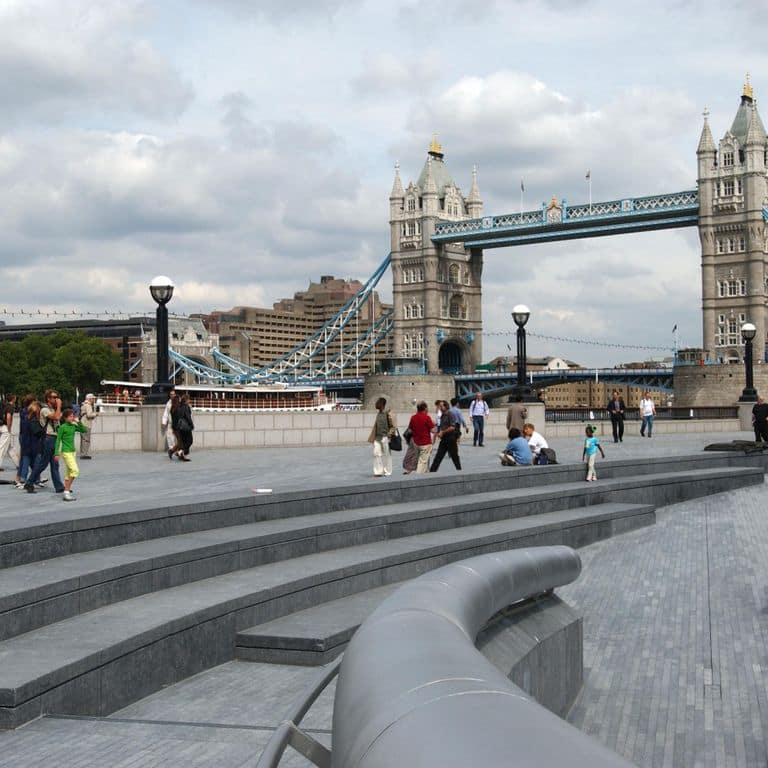 Application image for Kilkenny Limestone. The image shows this material being used for architectural elements, seating &amp; benches, patio pavers and treads. The surface finish shown is flamed. The dominant color shown is gray; with a blue secondary. The color mix creates a cool feeling. Regular color pattern.